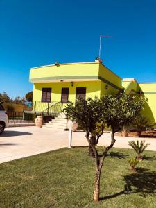 ein gelbes Gebäude mit einem Baum davor in der Unterkunft Mondoverde Apartments & Rooms in Surano