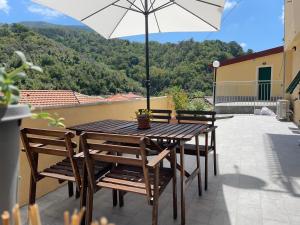 a wooden table with chairs and an umbrella on a patio at Cà di GIACO in Moneglia