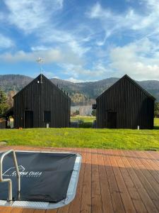 two black buildings with a bath tub on a deck at Czarna Chata Luxury Resort in Klimkówka