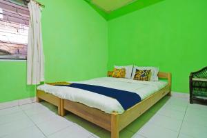 een slaapkamer met groene muren en een bed in een kamer bij SPOT ON 91543 Pondok Denki 11 in Bandung
