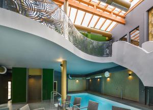 a swimming pool with a staircase in a building at Park Hotel Ambrózia in Hajdúszoboszló