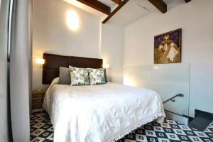 塞維利亞的住宿－Typical Sevillan 2 bedroom unit，卧室配有一张床,墙上挂有绘画作品