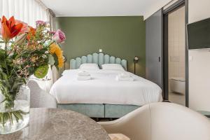 1 dormitorio con 1 cama y un jarrón de flores en Bens The Walton en Ámsterdam