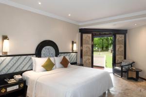 een slaapkamer met een groot wit bed en een glazen schuifdeur bij Discovery Kartika Plaza Hotel in Kuta