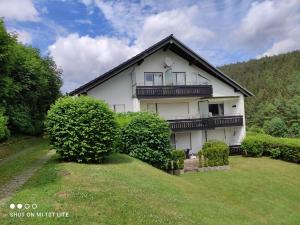 Cette maison blanche dispose d'un balcon au-dessus d'une cour. dans l'établissement Ferienwohnungen Lang, à Willingen