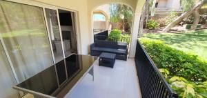 een balkon met een glazen tafel en een bank bij Golf del Sur-1 bedroom poolside apartment-sleeps 4 in San Miguel de Abona
