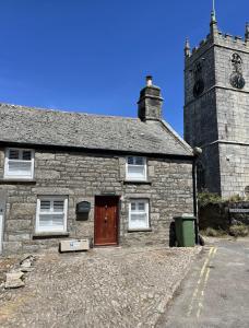 un antiguo edificio de piedra con una torre de reloj en Cobble Cottage en St Just