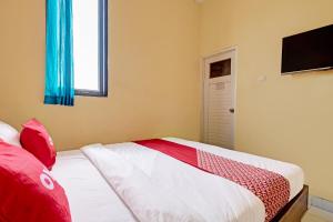 1 dormitorio con cama, ventana y TV en OYO 91532 Malioboro Guesthouse, en Yogyakarta