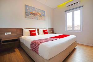 sypialnia z dużym łóżkiem z czerwonymi poduszkami w obiekcie Super OYO Collection O 91472 The Regia Dago w mieście Bandung