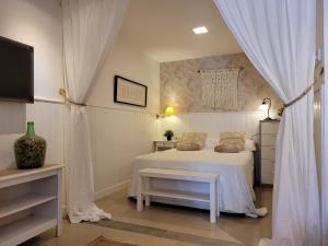 a bedroom with a white bed and a tv at "COZY LOFT", TERRACE, PARKING and SWIMMING POOL in Málaga