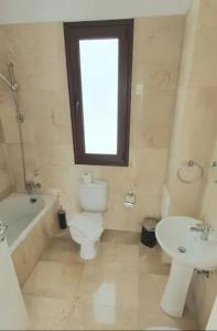 een badkamer met een toilet, een wastafel en een raam bij St. Georgiana Villa 7 in Peyia