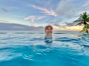 un joven nadando en una piscina en el océano en Maui Palms, en Korolevu