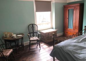 1 dormitorio con 1 cama, mesa y sillas en The Victorian House en Bridport