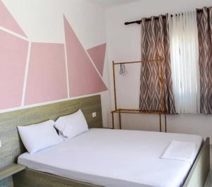 um quarto com uma cama com lençóis brancos em Troi beach house em Vlorë