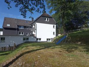 ein großes weißes Haus mit einem Spielplatz davor in der Unterkunft Smart Resorts Haus Saphir Ferienwohnung 504 in Winterberg