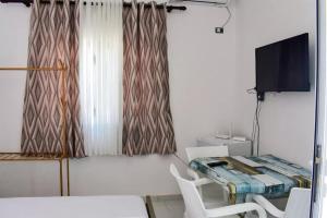 um quarto com uma mesa e cadeiras e uma televisão em Troi beach house em Vlorë