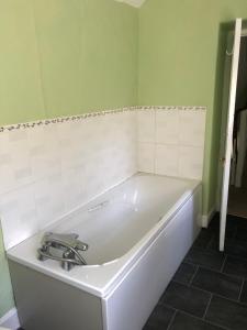 baño con bañera blanca y paredes verdes en The Victorian House en Bridport