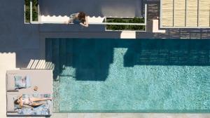 a woman sitting on a ledge next to a swimming pool at Epiphany Villas Lefkada in Tsoukalades