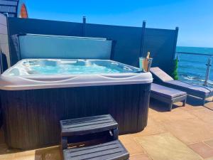 a jacuzzi tub on a patio with a bench at 3 Sinclair Bay Lodges in Keiss