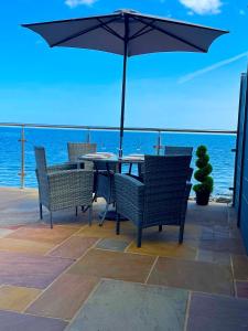 a patio with a table and chairs with an umbrella at 3 Sinclair Bay Lodges in Keiss