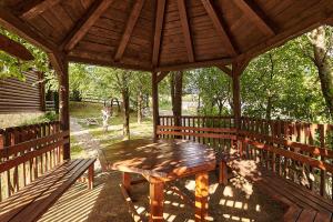a wooden gazebo with a wooden table and benches at Country House Brijest in Kolašin