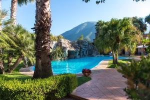 a pool with palm trees and a mountain in the background at Hotel Villa Albani in Nocera Superiore