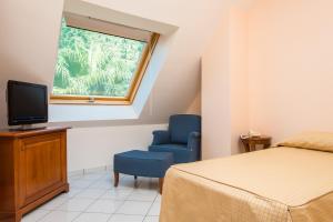 a bedroom with a bed and a blue chair and a window at Hotel Villa Albani in Nocera Superiore