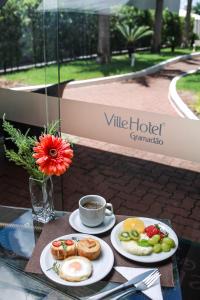 a table with two plates of food and a cup of coffee at Ville Hotel Gramadão in Votuporanga