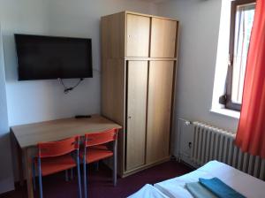 Cette chambre comprend un bureau et une armoire avec une télévision. dans l'établissement Penzion Beta, à Luhačovice