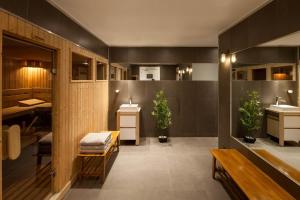 une salle de bains avec deux lavabos, un banc et deux plantes dans l'établissement Les Rives d'Argentière, à Chamonix-Mont-Blanc