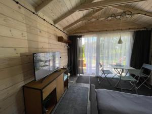 a living room with a television and a dining room table at Szarejkowy GLAMP in Szarejki
