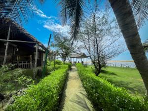 a path to the beach with a house and palm trees at Lotus Eco Resort Konark in Konārka