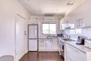 cocina con armarios blancos y nevera blanca en Beach apartment 10/22 esplanade sea-views, en Glenelg