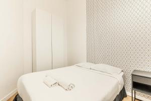 ein weißes Schlafzimmer mit einem Bett mit Handtüchern darauf in der Unterkunft 08 Design Flat Republique in Paris