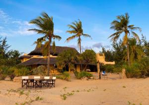 a house on the beach with tables and palm trees at Jahazi House in Lamu