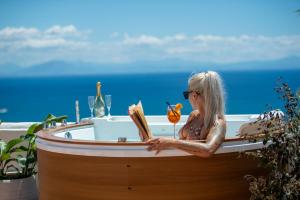 a woman sitting in a bath tub reading a book at Villa Algarrobos in Praiano