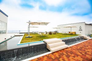 a rooftop patio with a pool and tables and umbrellas at BAYSIDE KANAYA in Futtsu