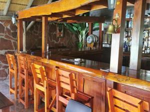 bar z drewnianymi krzesłami i drewnianym blatem w obiekcie Palmeiras Lodge Oshikango w mieście Oshikango