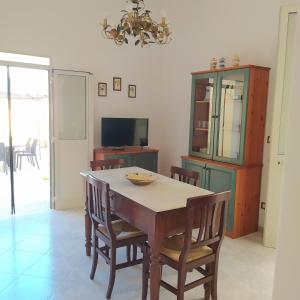 een eetkamer met een tafel en stoelen en een televisie bij La casetta con cortile in Lecce