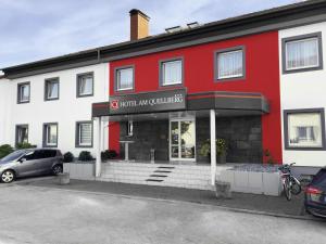 un edificio rojo y blanco con un coche aparcado fuera en Hotel Am Quellberg, en Recklinghausen