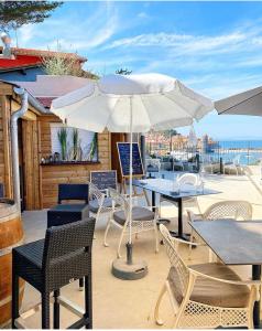 eine Terrasse mit Tischen, Stühlen und einem Sonnenschirm in der Unterkunft Hotel Le Bon Port in Collioure