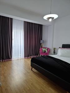 a bedroom with a large bed and a pink chair at AryaHome in Bistriţa