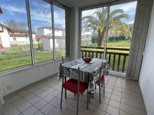 a table and chairs in a room with windows at Studio Cambo-les-Bains, 1 pièce, 2 personnes - FR-1-495-63 in Cambo-les-Bains