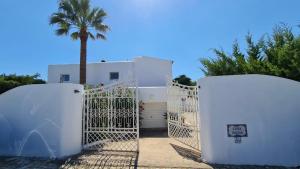 een wit huis met een poort en een palmboom bij CASA SACHA in Carvoeiro