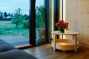 uma mesa com um vaso de flores ao lado de uma janela em Unique Tiny House at Saaremaa Golf & Country Club em Kuressaare