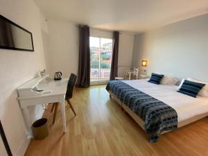 a bedroom with a bed and a desk and a window at Hotel Le Bon Port in Collioure