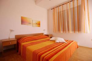 ein Schlafzimmer mit einem Bett mit einer orangefarbenen gestreiften Decke in der Unterkunft Apartments by the sea Ist - 19193 in Ist