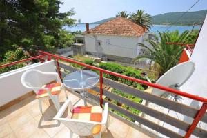 a balcony with a table and chairs and a house at Apartments by the sea Ist - 19193 in Ist