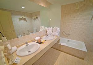 a bathroom with a sink and a tub and a mirror at Holiday World RIWO Hotel. in Benalmádena