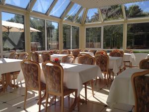 a dining room with tables and chairs and windows at Hotel Am Quellberg in Recklinghausen